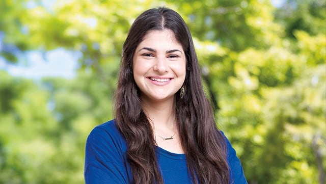 An image of a young student against a lush background.