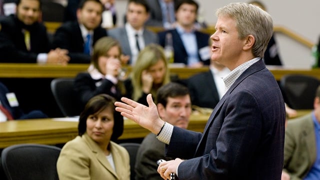 An executive speaks to a full class of students.