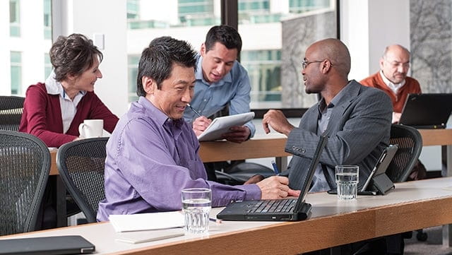 A group of seasoned professionals collaborate together while working in a classroom.