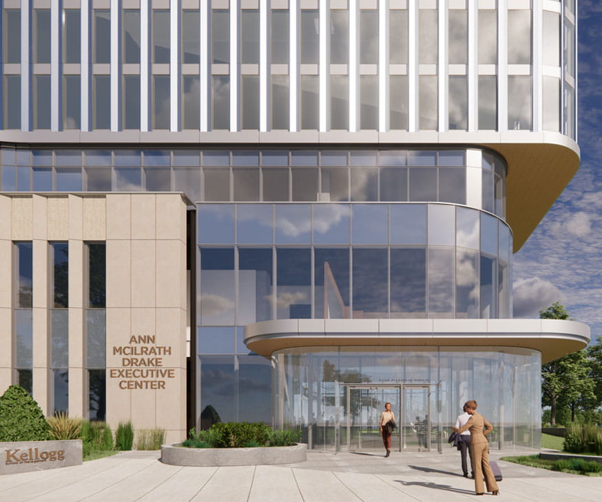 Several people in suits walking into the glass entrance of the Ann McIlrath Drake Executive Center. In the background there's a blue sky with white and grey clouds and trees beside the building.