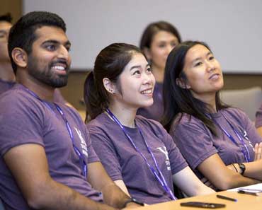 Group of Kellogg students in a classroom wearing purple shirts
