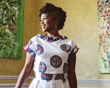 Alumna Ugochi Nwoga in front of colorful artwork