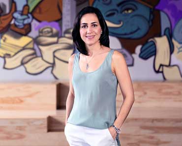 Alumna Cristina Junqueira standing in front of a colorful mural