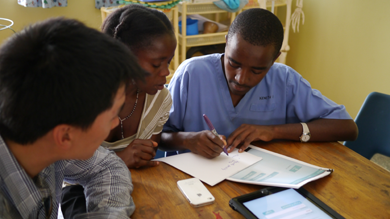 Eric Chang '13 (left) demonstrates the Northwestern Global Health Foundation's tablet prototype to two nurses in a clinic in Mbarara, Uganda. Chang was one of 34 Northwestern students in the inaugural Innovate for Impact course this year. 
