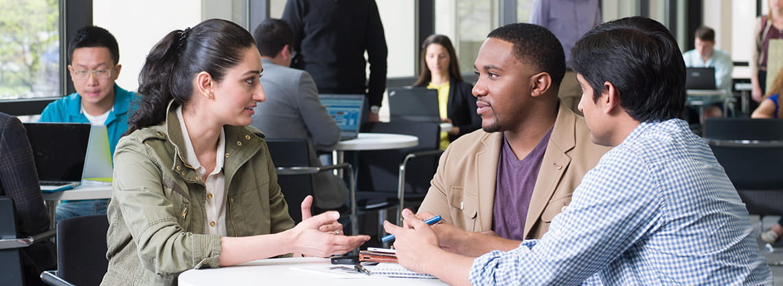 A diverse group of students collaborate together at a table.