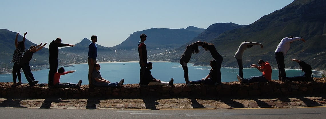 Students spell Kellogg with various poses in a mountainous landscape.