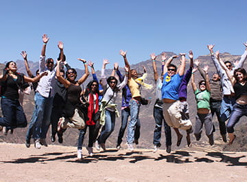Students jump and pose mid air in a mountainous region.