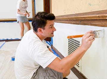 A young man volunteers by painting a classroom.