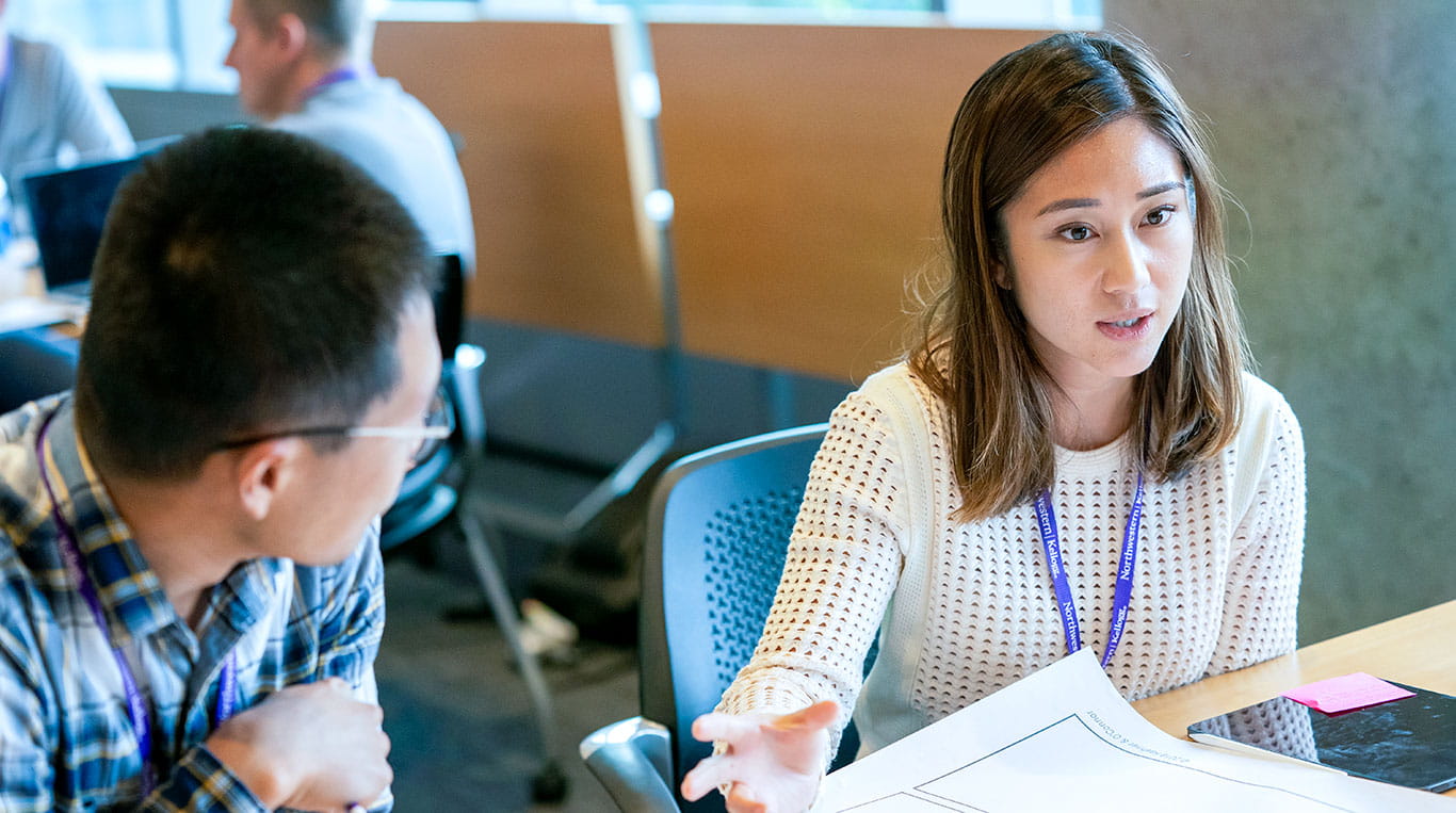 Two Kellogg students seated at a table having a discussion