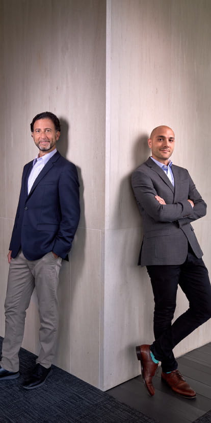 Kellogg professors Eli Finkel and Nour Kteily standing at the corner wall looking towards the viewer