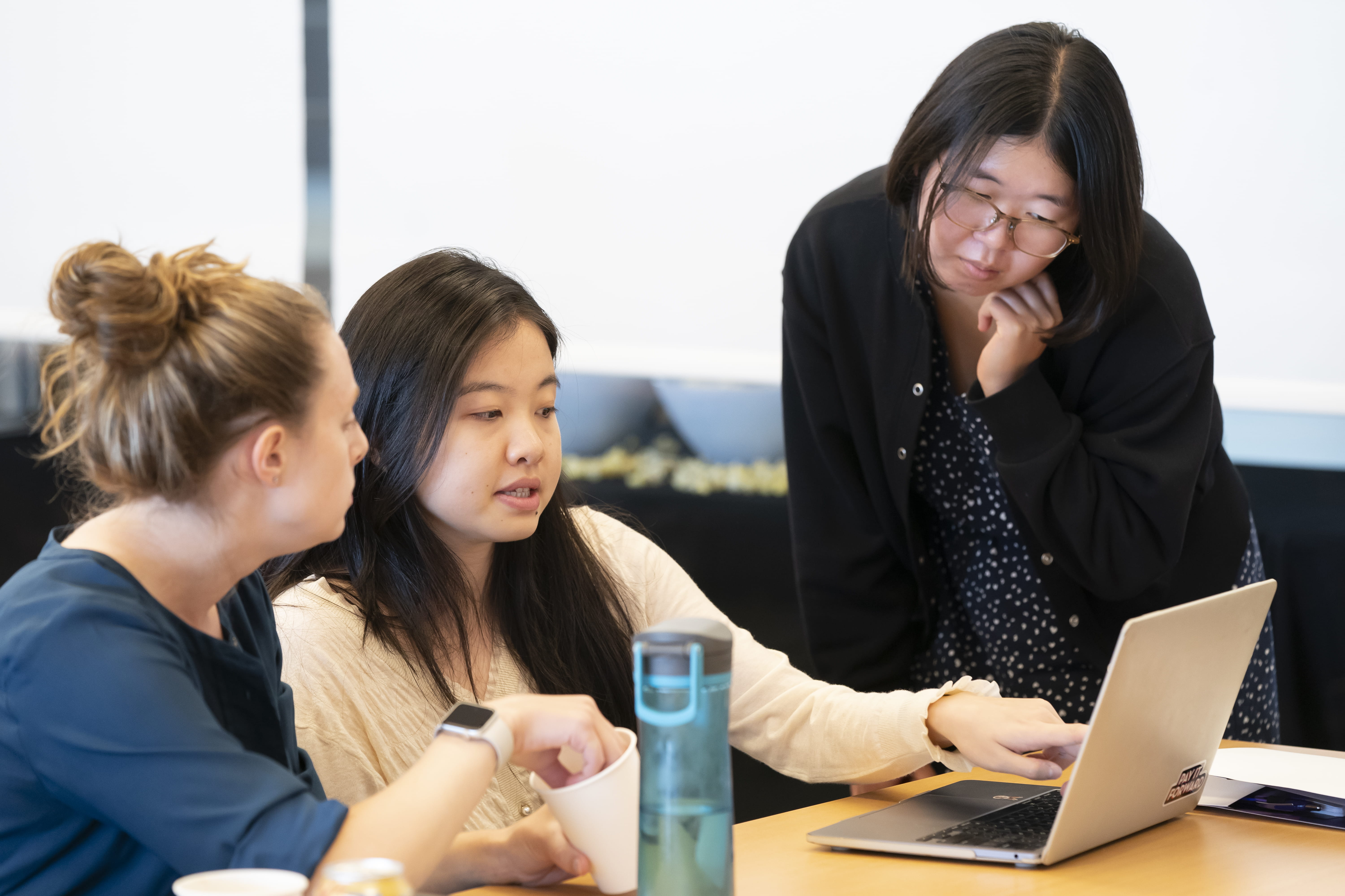 Event attendees gather around a laptop to discuss materials