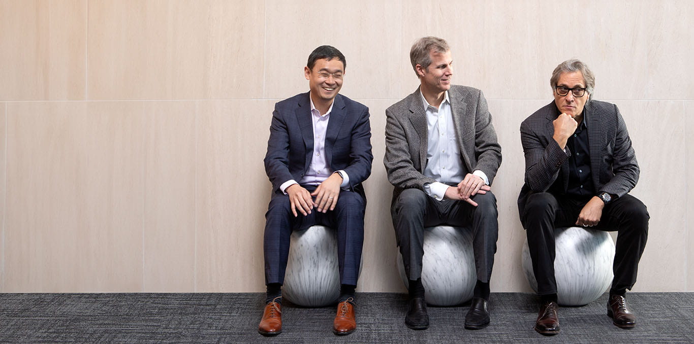 Three Kellogg professors, Dashun Wang, Benjamin F. Jones, and Brian Uzzi, seated against a wall.