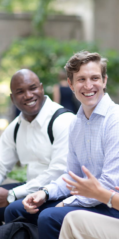 Three part-time MBA students sitting outside on campus.