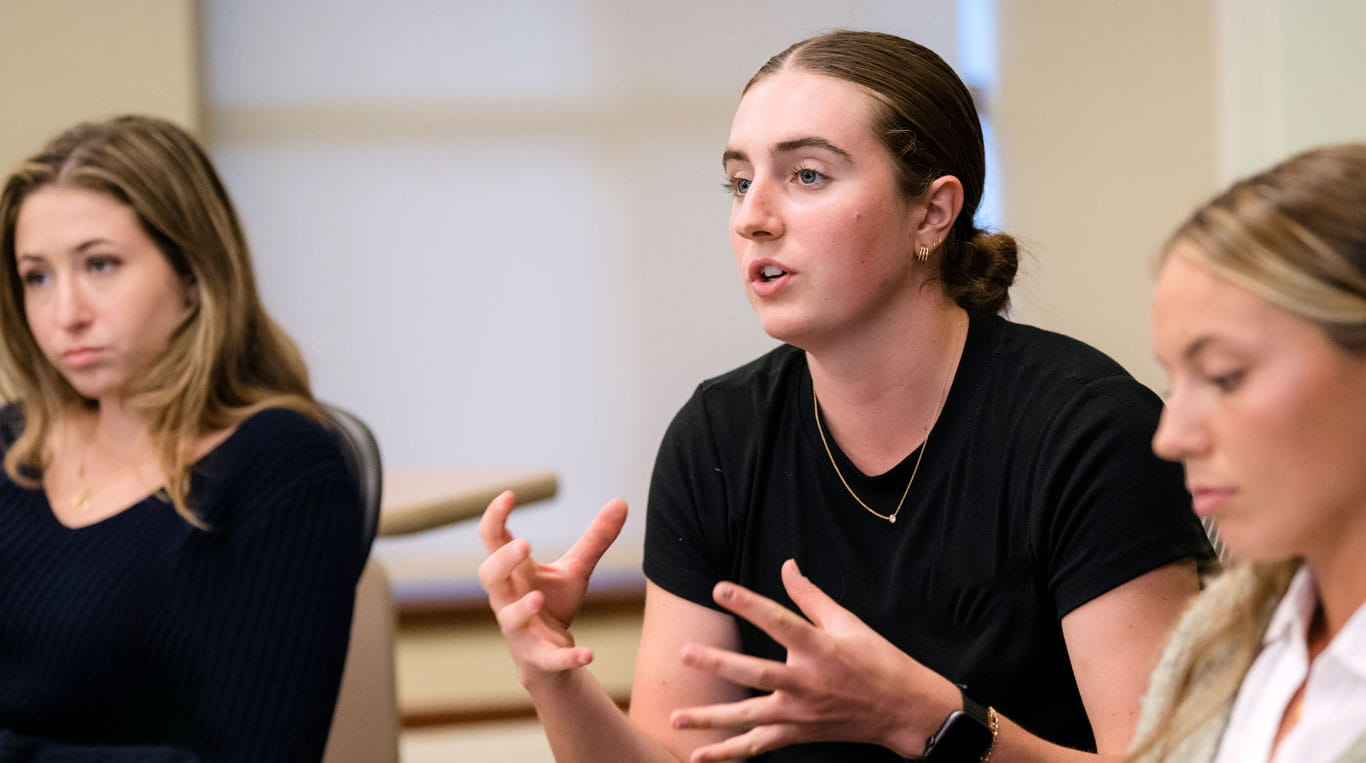 Student explains their thoughts during a class at Kellogg as other students listen.