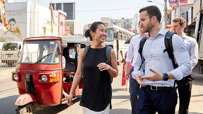 A group of Kellogg MBA students chatting while walking alongside a bustling street in Asia