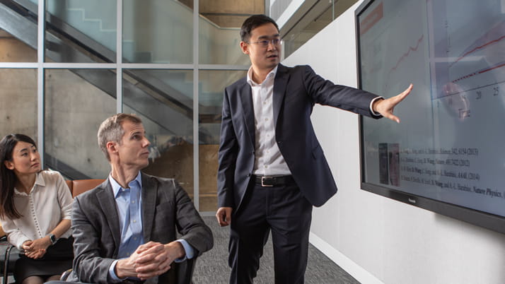Kellogg professors Dashun Wang and Ben Jones review research data on a touchscreen at the Kellogg Global Hub