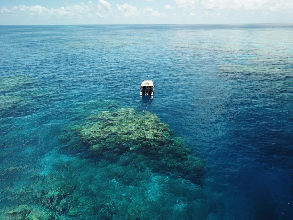 A small boat in the middle of a blue ocean reef