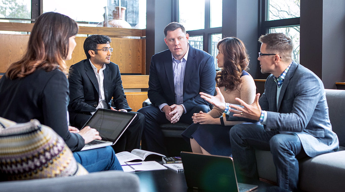 A group of five people talk while sitting down in a building on Northwestern University's campus