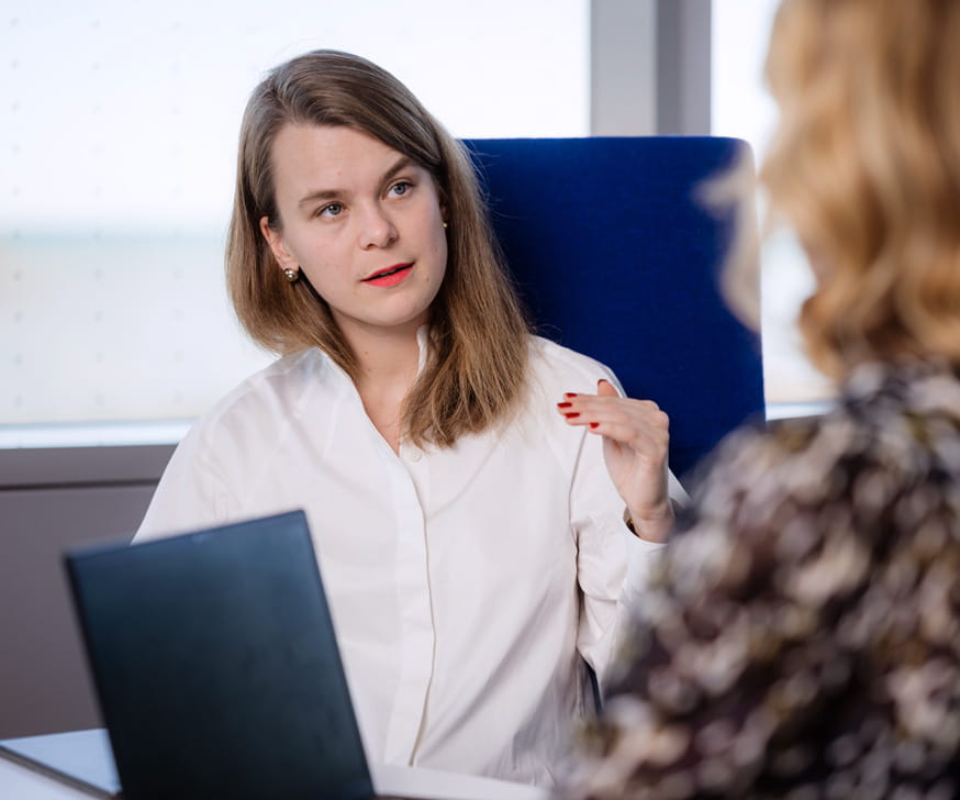Two women sitting in chairs talking with each other.