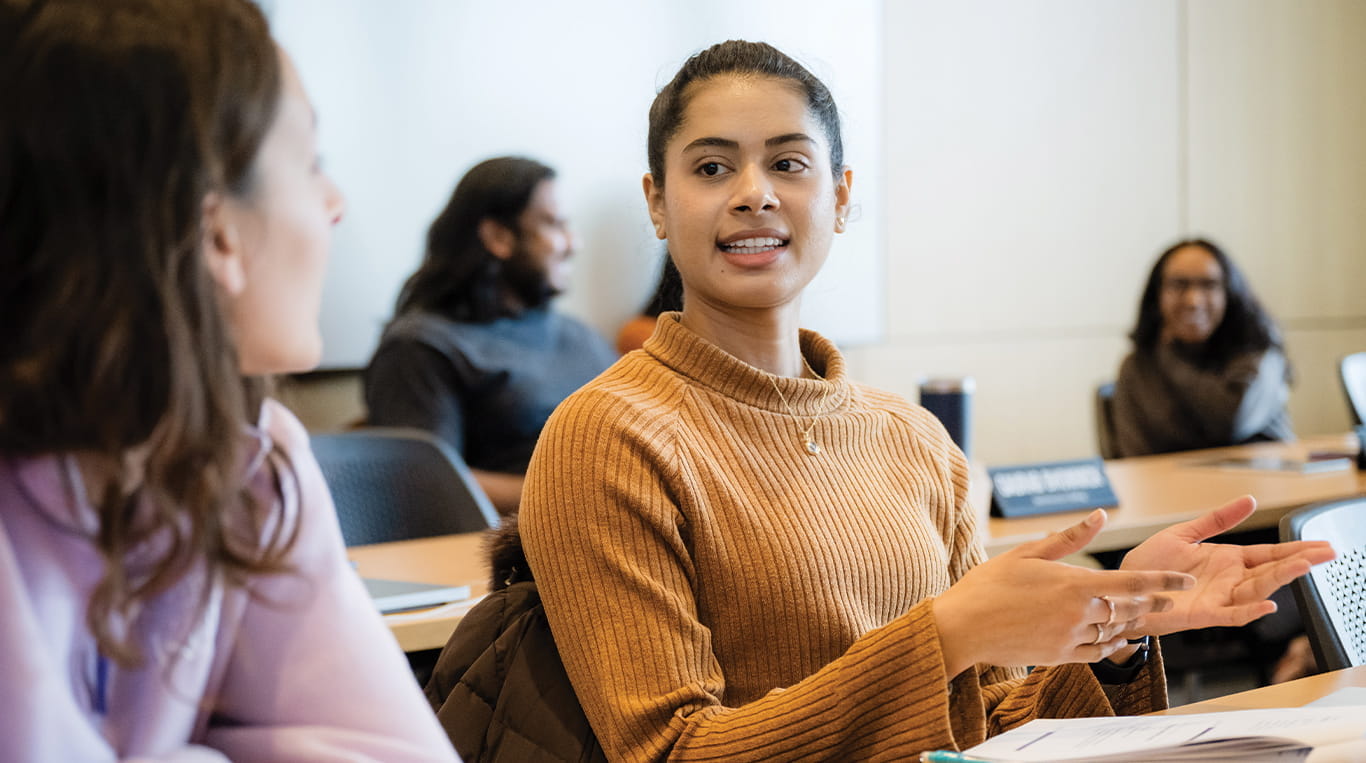 Two students have a conversation in a Kellgg classroom 