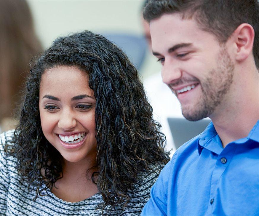Two smiling, casually-dressed Kellogg MS in Management Studies students look towards the bottom left