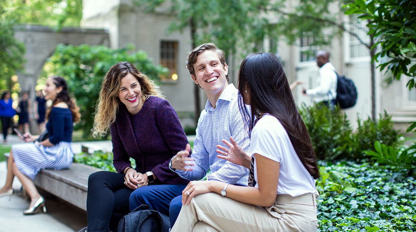 Three Kellogg Part-Time MBA students seated outside on the Wieboldt campus