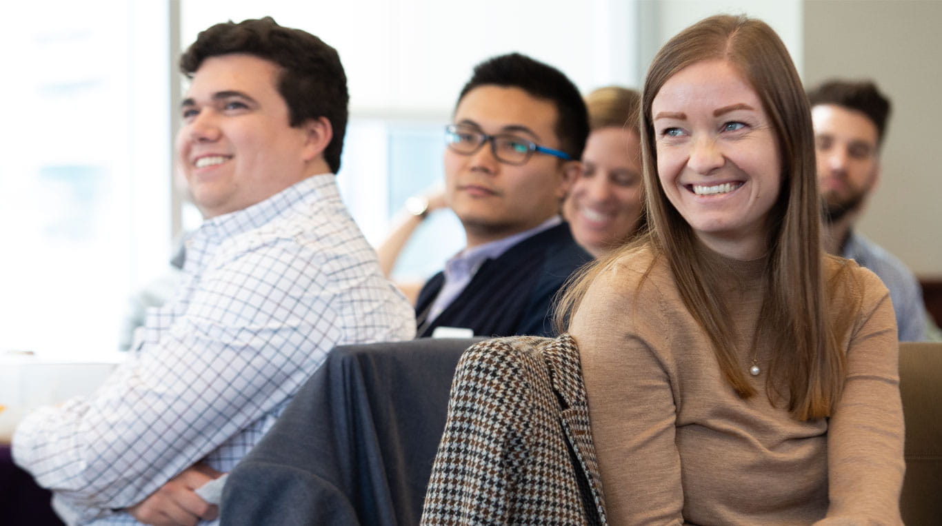 Five Northwestern Kellogg students sit around tables smiling
