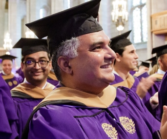 Kellogg Executive MBA graduates in cap and gown, gathered in the chapel for graduation