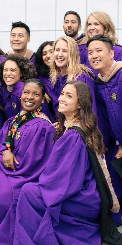 Kellogg MBA students posing outside of the Kellogg Global Hub in their purple gowns