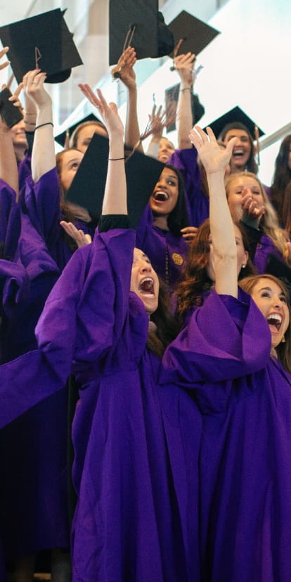 Kellogg graduates on the steps of the Global Hub, throwing their caps into the air