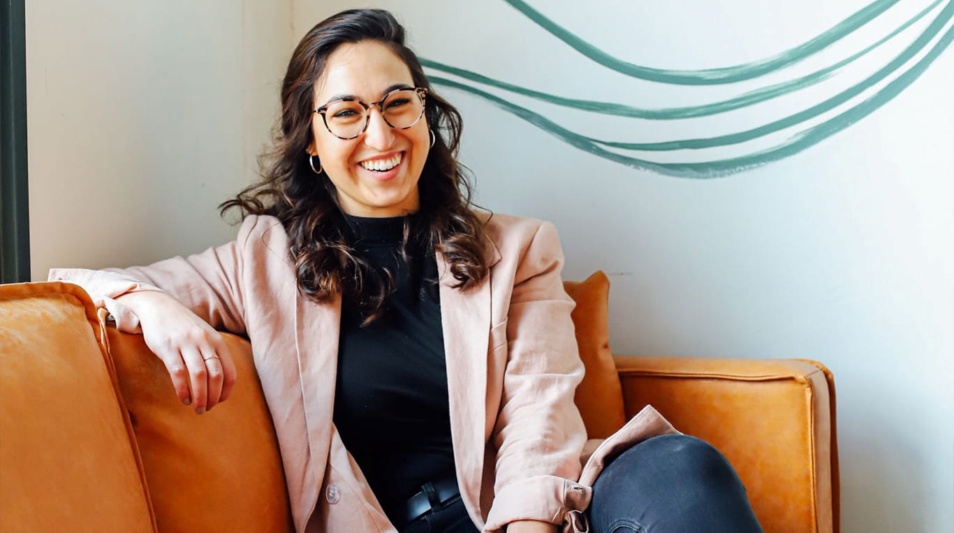 Kellogg student Ale Trevino sitting on an orange sofa