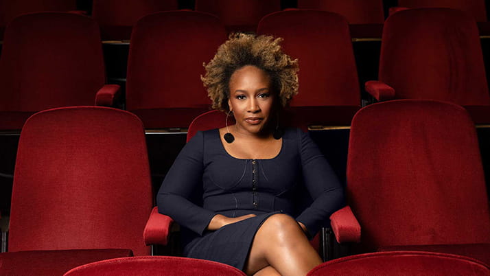 Kellogg alumna Ukonwa Ojo pictured sitting in a movie theatre with dark red velvet chairs