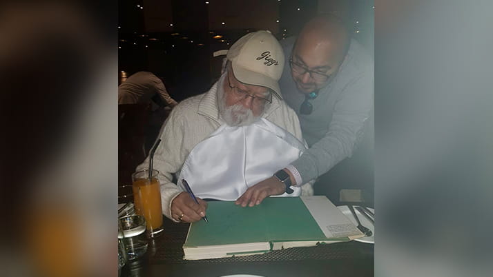 Ajit Kalra with his father, culinary author Jiggs Kalra, who signs a book for a fan