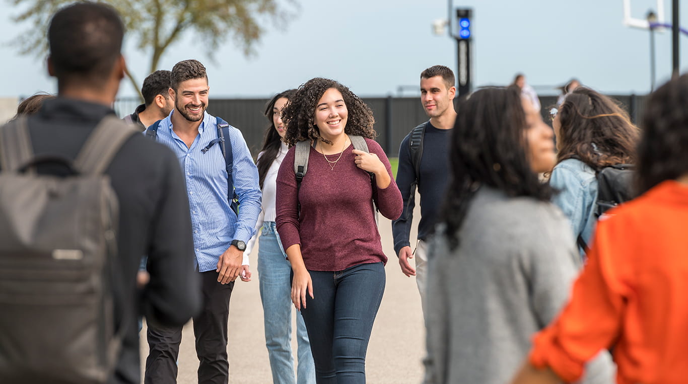 Students wearing backpacks walking along a pathway on campus