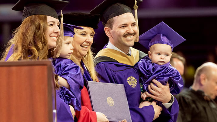 Kellogg MBA graduates with their babies on stage at convocation