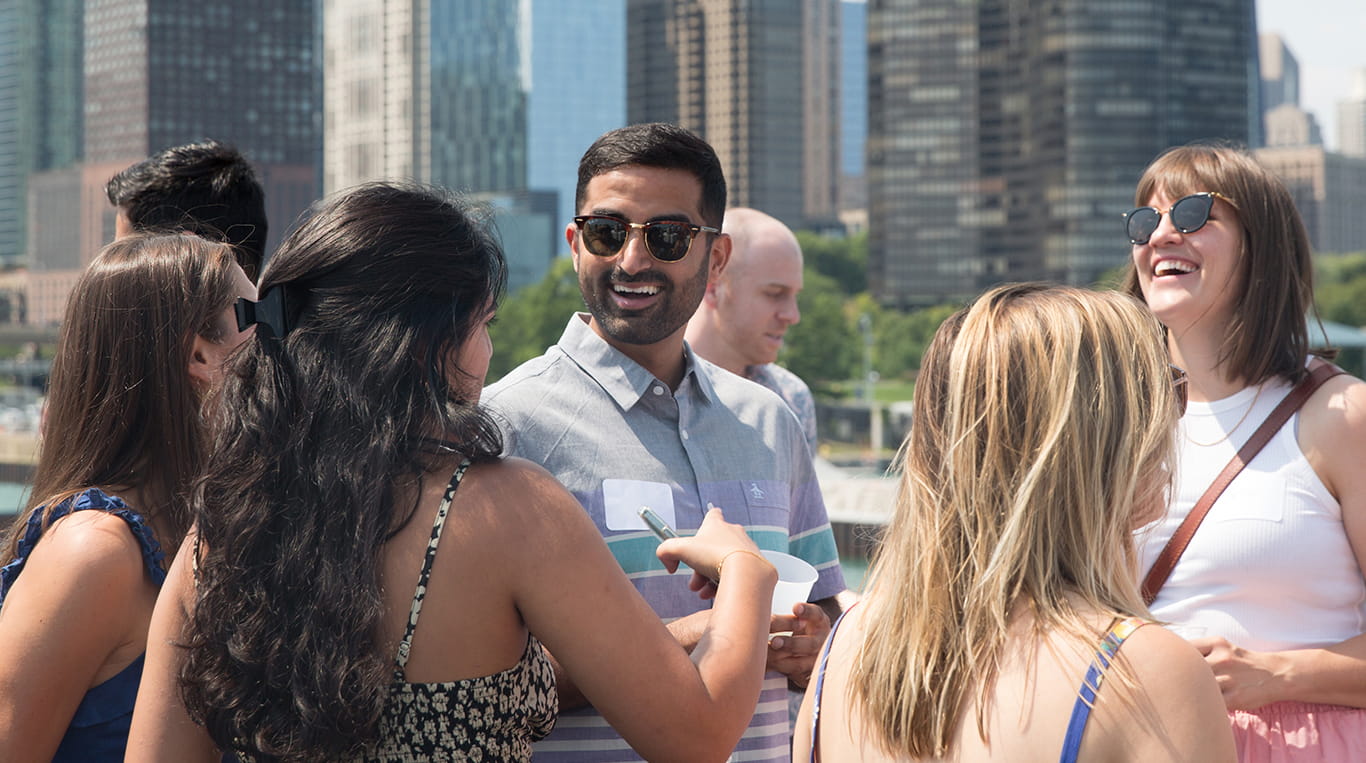 Kellogg students mingling at an outdoor event with a city skyline in the background