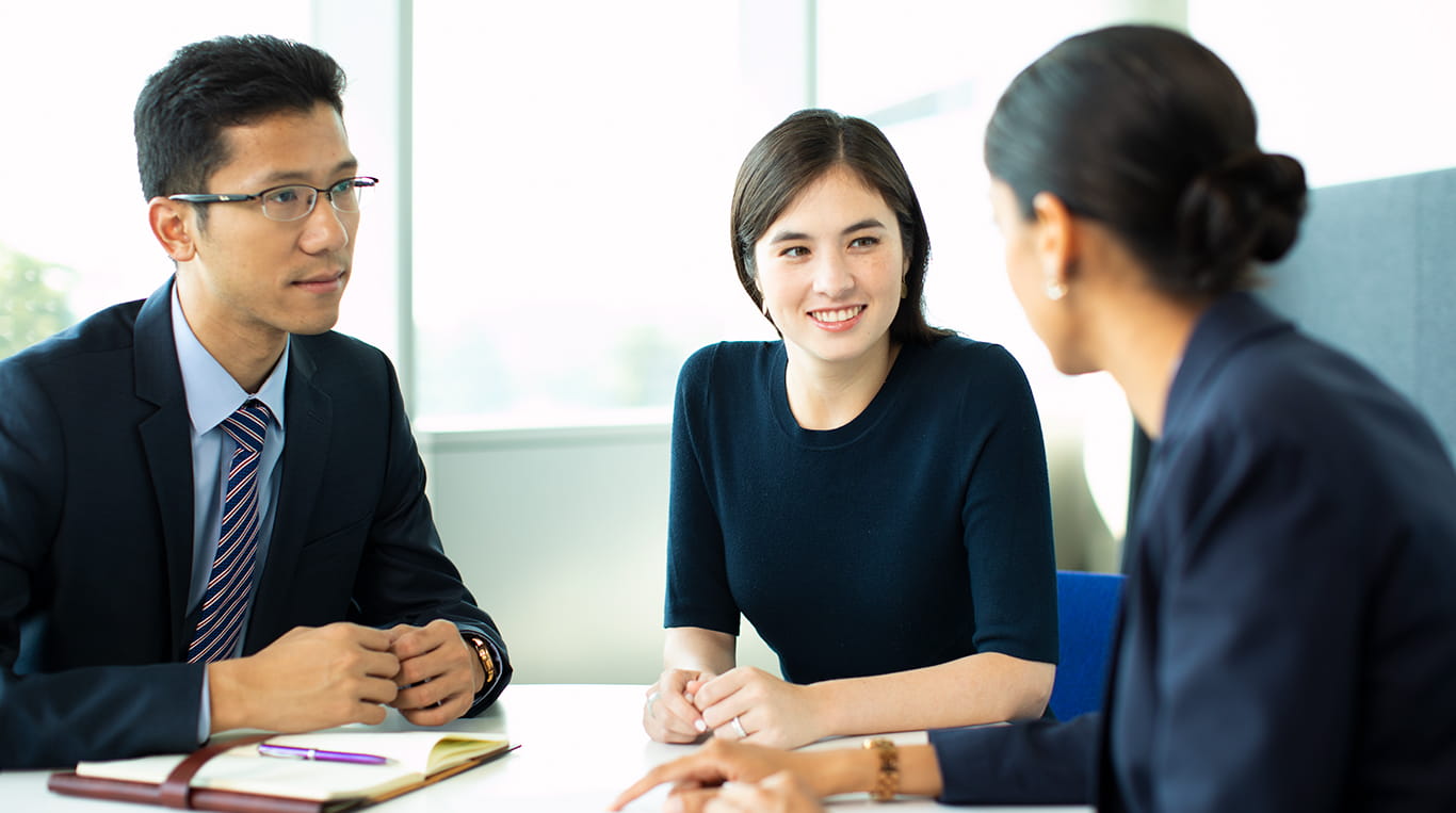 Three people in business attire sitting around a table during an in-person interview