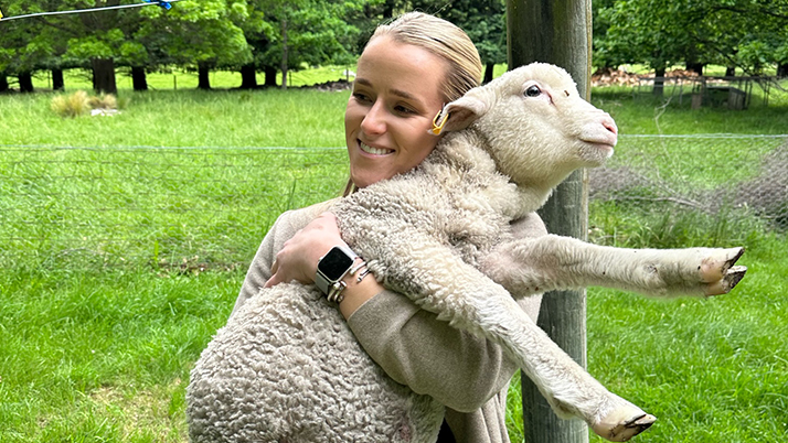 Audrey Melville holding a sheep at a farm in New Zealand