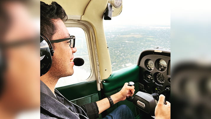 Kellogg student Maanil Dodani, MMM Program, sits in the cockpit of a small plane as he flies the aircraft