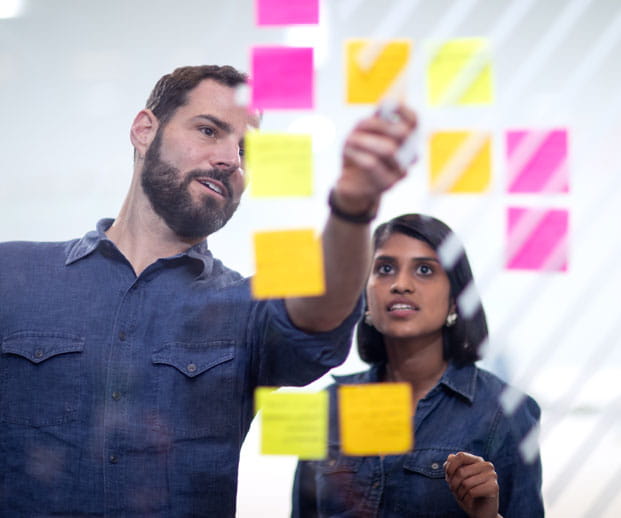 Kellogg entrepreneurship professor David Schonthal and a student talk while looking at ideas written on colorful sticky notes.