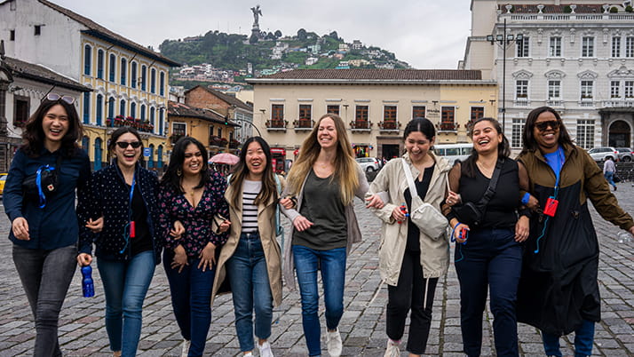 Kellogg students link arms and walk down the street while on a trip to South America