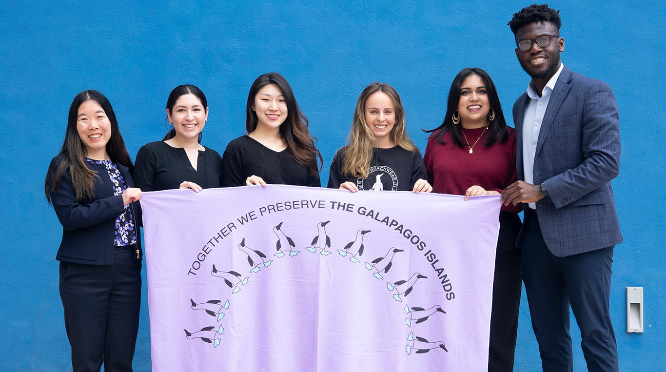 Kellogg student Nayna Anwar and classmates hold a white towel with the words "Together we preserve the Galapagos Islands"