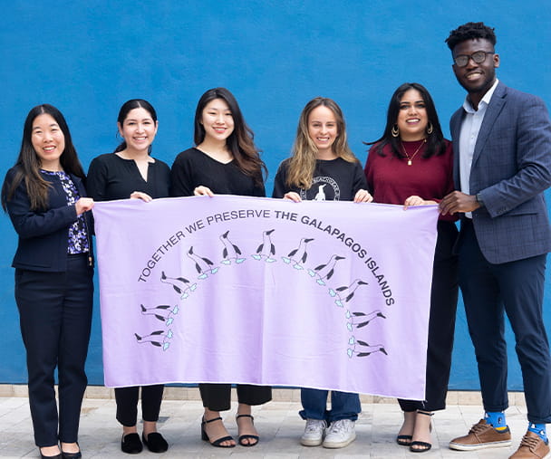 Kellogg student Nayna Anwar and classmates hold a white towel with the words "Together we preserve the Galapagos Islands"