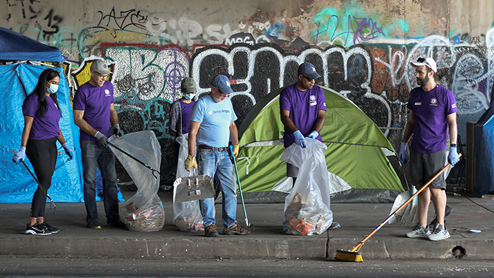 A group of Kellogg alumni clean up trash beneath a highway underpass