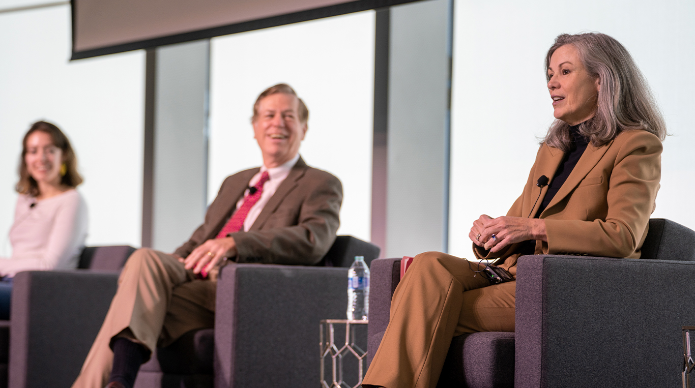 Footlocker CEO Mary Dillon wears a tan suit and sits in a purple chair during a panel discussion at the Kellogg School of Management