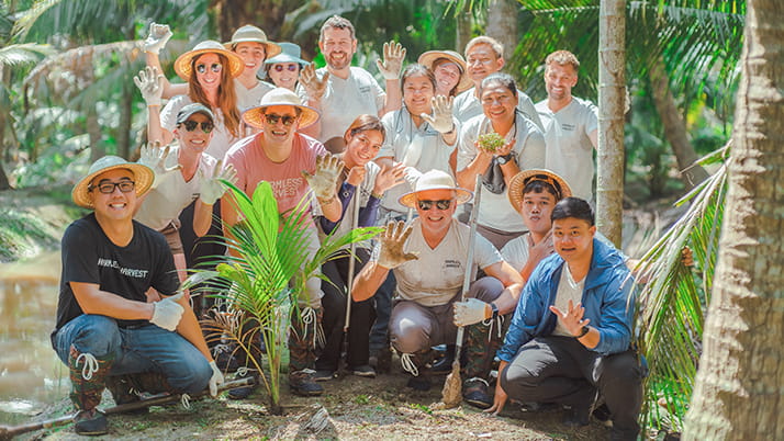 The Harmless Harvest team poses for a group photo in a tropical setting