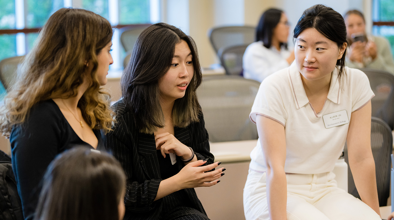 Four students in the Master's in Management Program stand in a classroom having a group discussion