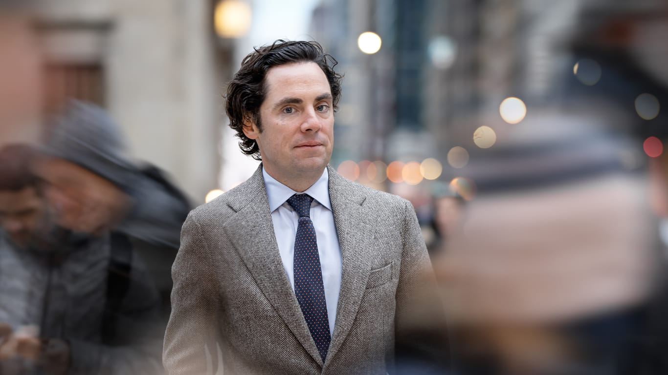 Harris Poll CEO Will Johnson stands on a busy sidewalk in Chicago as pedestrians pass by around him.