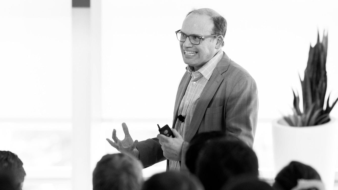 Black and white phot of Professor Jose Liberti standing on stage and speaking to a crowd