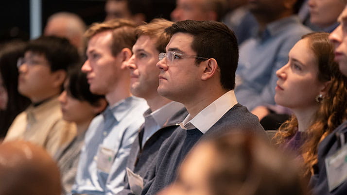Kellogg students sit in an audience and listen intently to a presentation.